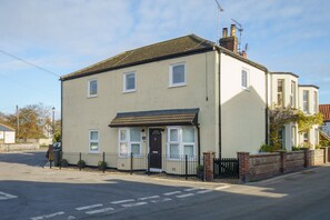 A two-story residential building with a flat roof, a front door, and a small porch. - Rothwill House | Stylish Dog Friendly Apartment Near the Beach (Winterton-on-Sea)