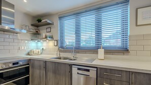 Eine moderne Küche mit Einbauofen, Geschirrspüler und großem Fenster mit Jalousien.