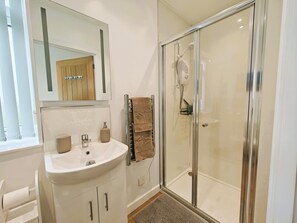 Une salle de bain moderne avec une douche à parois de verre, un lavabo blanc et un meuble-lavabo en bois.