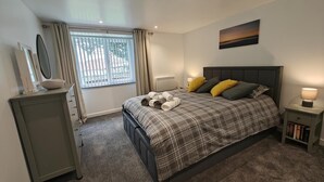 A bedroom with a bed, bedside tables, a window with curtains, a painting on the wall, and a bedside lamp. - 2 Bed in Tankerness (oc-q32730) (Tankerness)