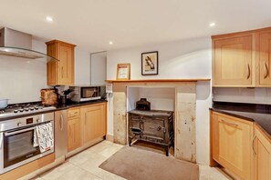 A kitchen with wooden cabinets, a stove, a microwave, and a vintage stove.