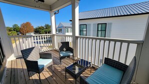 A covered outdoor deck with wicker furniture and a glass table. - Luxury Pet-friendly Home With Game Room & Community Pool (Orange Beach)
