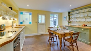 A kitchen with a wooden dining table, chairs, a sink, and a window. - 2 Bed in Walberswick (oc-hhock) (Walberswick)
