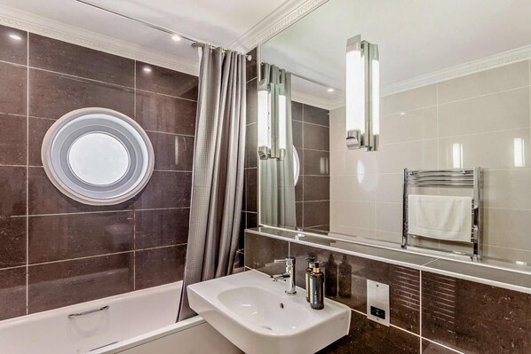 A modern bathroom with a bathtub, a sink, and a large mirror. - 2 Bed in Bath (oc-bhr16) (Bath)