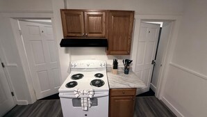 A compact kitchen with a white stove, wooden cabinets, and a marble countertop. - 3BR Hamden Stay Near Yale, Southern, Quinnipiac & New Haven (Hamden)