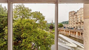 A view through a window of a river with a bridge, trees, and historic buildings. - 2 Bed in Bath (oc-bhr6) (Bath)