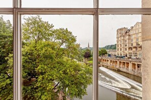 A view through a window of a river with a bridge, trees, and historic buildings. - 2 Bed in Bath (oc-bhr6) (Bath)