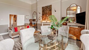A spacious living room with a glass coffee table, a fireplace, a television, and a dining area. - 2 Bed in Bath (oc-bhr6) (Bath)