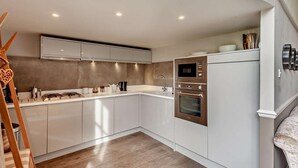 A modern kitchen with white cabinetry, a built-in oven, and a microwave. - 2 Bed in Bath (oc-bhr6) (Bath)