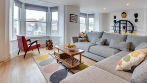 Uma sala de estar moderna com um sofá cinzento, uma poltrona vermelha e uma mesa de centro de madeira.