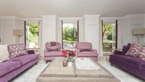 A spacious living room with two purple sofas, a coffee table, and a large window with a view of greenery. - 7 Bed in Combe Hay (oc-bhr21) (Combe Hay)