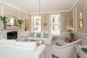 A well-lit living room with a fireplace, a sofa set, a coffee table, and a chair. - 3 Bed in Bath (oc-bhr53) (Bath)