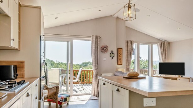 A modern kitchen with a large island, a dining area with a view, and a flat-screen TV. - 2 Bed in Upton (oc-h32761) (Ryde)