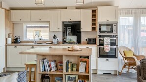 A modern kitchen with white cabinets, a wooden countertop, and a built-in bookshelf. - 2 Bed in Upton (oc-h32761) (Ryde)