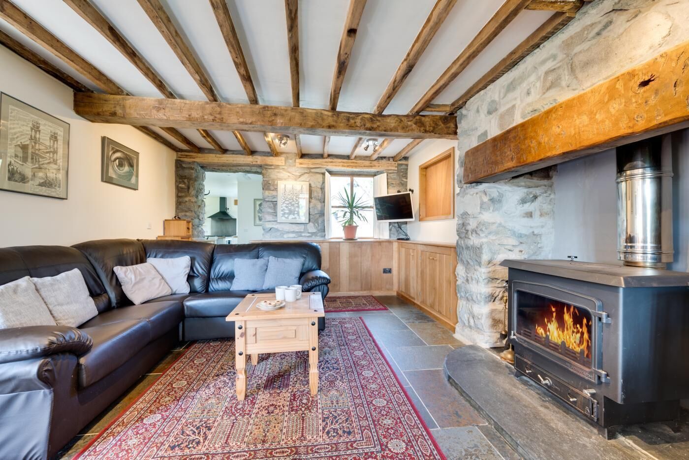 A cozy living room with a stone fireplace, a leather sofa, and a wooden coffee table.