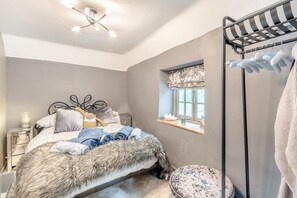 Une chambre à coucher comprenant un lit, une table de chevet, une fenêtre avec vue, un plaid en fourrure et un porte-vêtements suspendu.