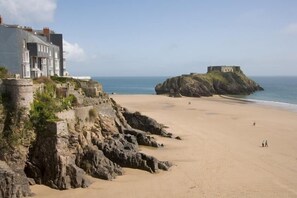 A coastal hotel with a large building overlooking a sandy beach and a historic fort on a nearby cliff. - 3 Bed in Penally (oc-pw9221) (Penally)