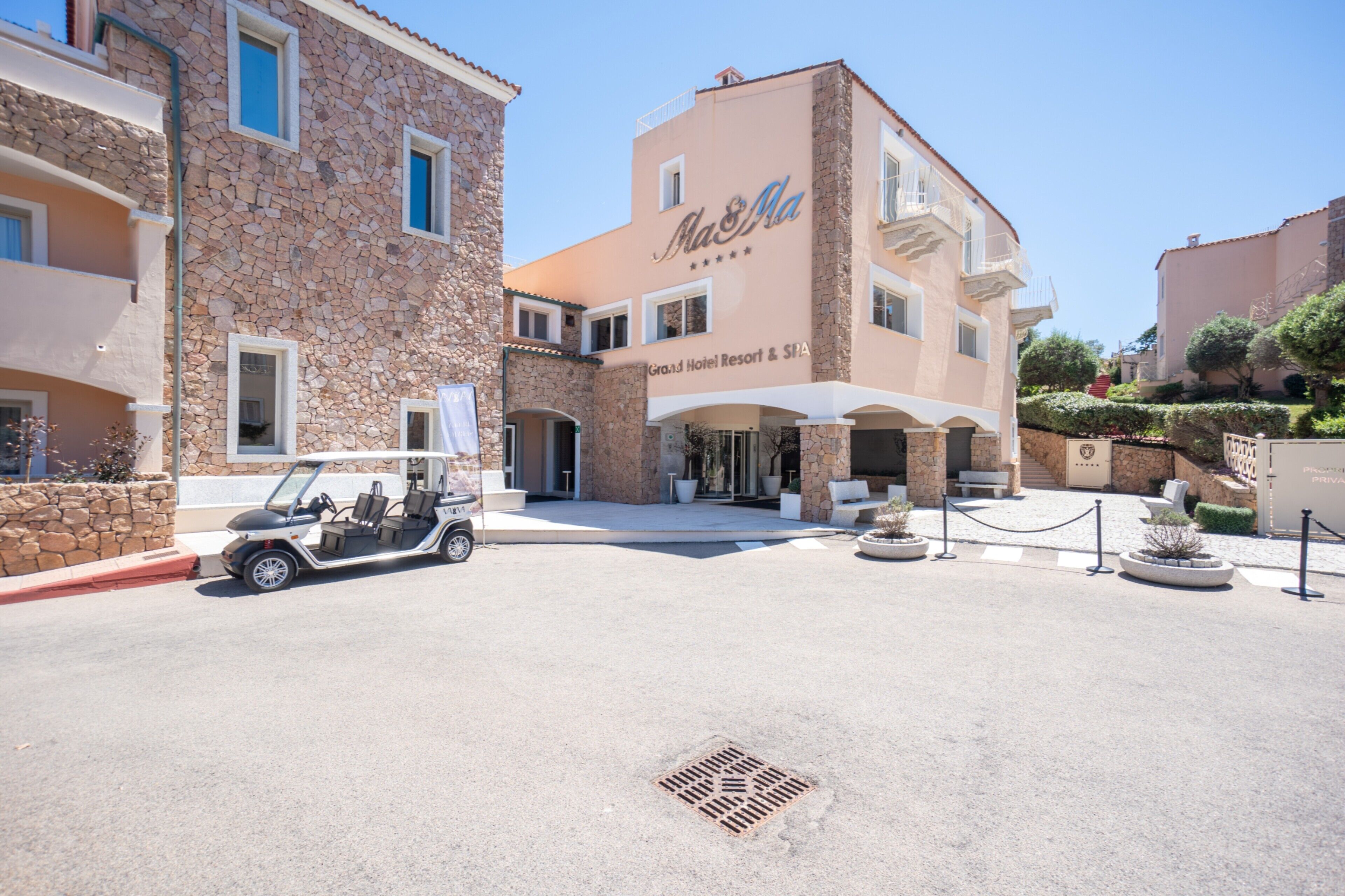 A hotel with a stone facade, a sign reading 'Grand Hotel Resort & Spa,' and a golf cart parked in front.