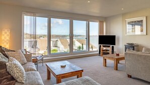 A spacious living room with a large sliding glass door leading to a balcony, a flat-screen TV, and a comfortable seating area. - 3 Bed in Saundersfoot (oc-pw522a) (Saundersfoot)