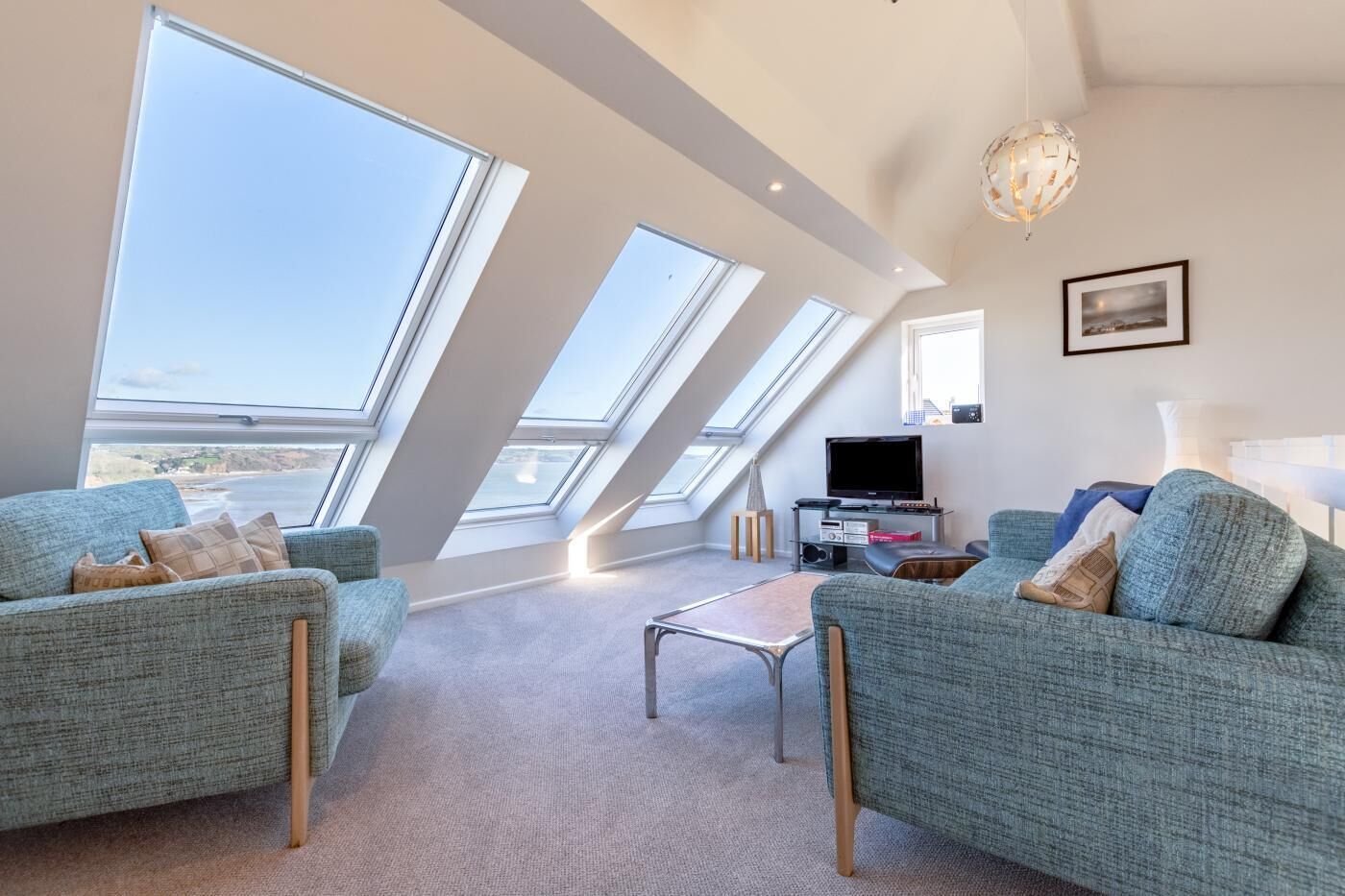Un salon moderne doté d’une grande fenêtre offrant une vue panoramique, d’un téléviseur à écran plat et d’un coin salon confortable.