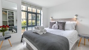Un dormitorio con una cama grande, mesitas de noche, un espejo y vistas al exterior.