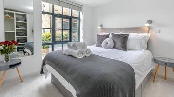 A bedroom with a large bed, bedside tables, a mirror, and a view of the outside.
