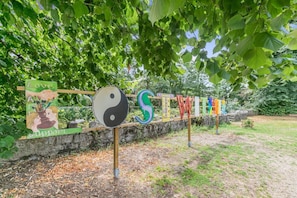 Un jardin entouré d’une clôture en bois, d’un mur de pierre et d’un panneau portant le symbole du yin et du yang.
