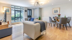 Una sala de estar moderna con un sofá, una mesa de comedor, sillas y un ventanal grande.
