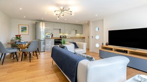 Una sala de estar moderna con sofá, comedor, cocina y televisor.