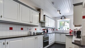 Een moderne keuken met witte kasten, zwarte aanrechtbladen en rode accenten.