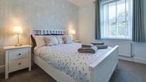 Een slaapkamer met een bed, twee nachtkastjes, een raam met gordijnen en een radiator.