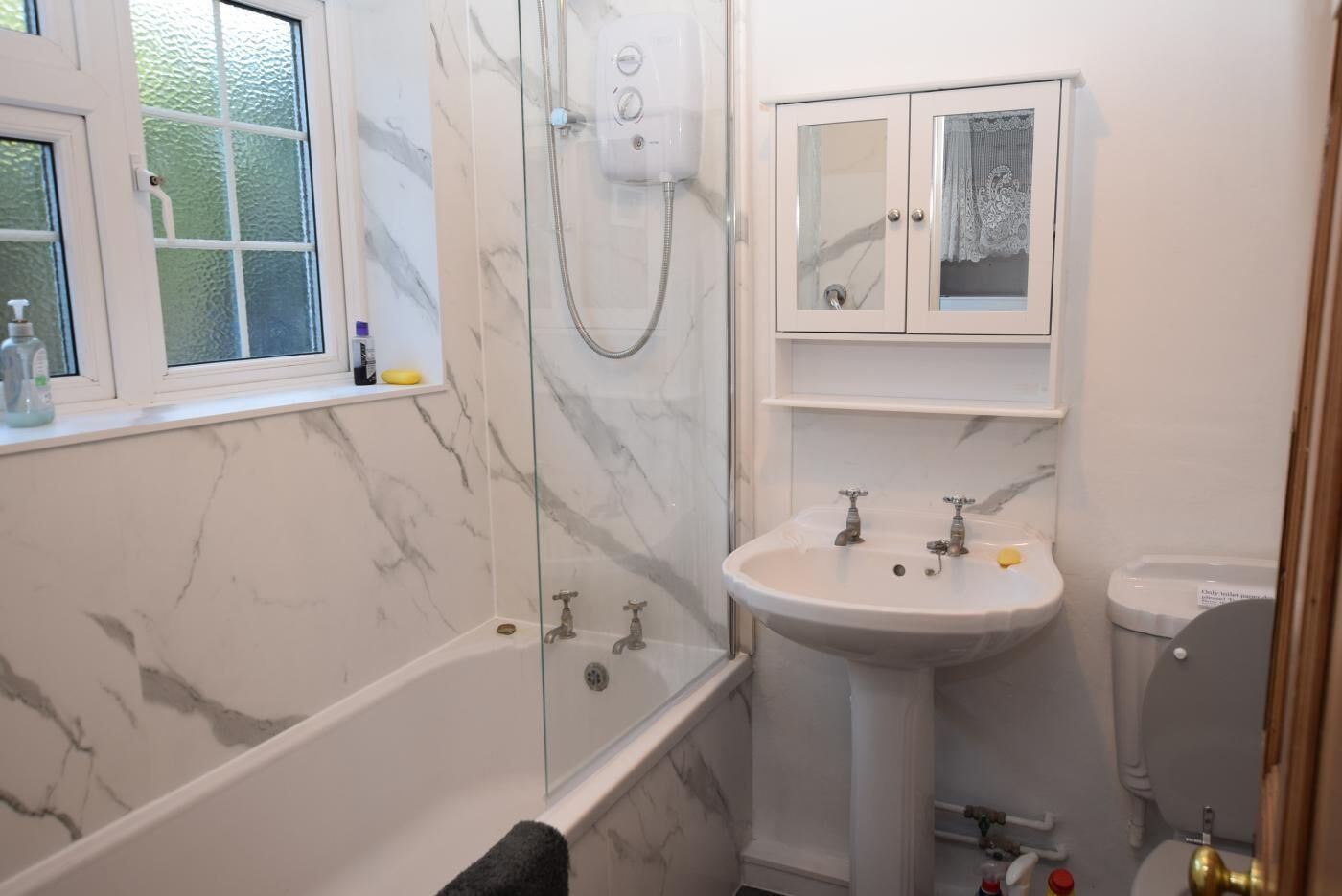 Une salle de bain comprenant une baignoire, une douche à parois de verre, un lavabo et des toilettes.