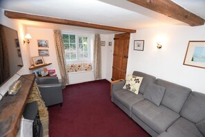 A cozy living room with a grey sofa, a wooden bench, and a red carpet.
