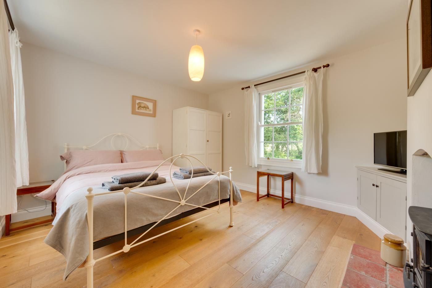 Une chambre à coucher avec un lit, une fenêtre, une télévision et une cheminée.
