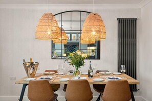 A dining area with a wooden table set for six, two large woven pendant lights, and a large mirror above the table. - 2 Bed in Saundersfoot (oc-pw252a) (Saundersfoot)