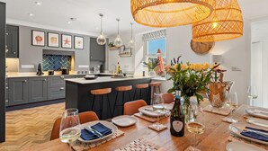 A modern kitchen with grey cabinets, a central island, and pendant lighting. - 2 Bed in Saundersfoot (oc-pw252a) (Saundersfoot)