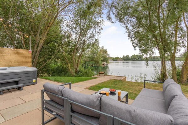 An outdoor patio with a gray sofa, a hot tub, and a table with snacks and drinks. - 1 Bed in Langtoft (oc-l32679) (Langtoft Fen)