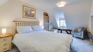 Une chambre à coucher avec un lit, des lampes de chevet, un bureau, une chaise, un tableau et une fenêtre.