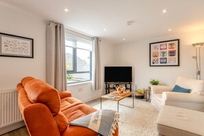 A modern living room with a sofa, a coffee table, a TV, and artwork on the walls.