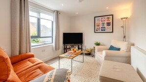 A living room with a sofa, a coffee table with books, a TV, and a painting on the wall. - 2 Bed in Holt (oc-l31797) (Holt)
