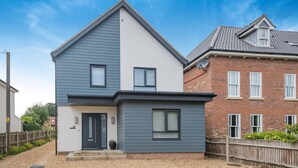 A two-story house with a grey and white exterior, a black front door, and a small front porch. - 2 Bed in Holt (oc-l31797) (Holt)