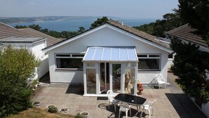 Une maison dotée d’un patio, d’un espace salon couvert et offrant une vue sur la mer.