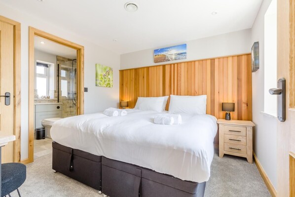 A hotel room with a large bed, wooden headboard, bedside tables, a mirror, and a painting on the wall.