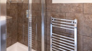 A modern bathroom with a glass shower enclosure, a chrome towel rack, and a wall-mounted towel warmer. - 2 Bed in Buxton (oc-dcwyn) (Tideswell)
