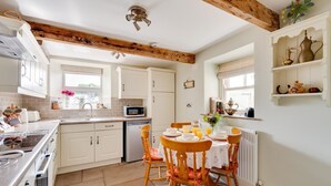 A kitchen with white cabinets, a wooden ceiling, and a dining table set with plates and cups. - 2 Bed in Buxton (oc-dcwyn) (Tideswell)