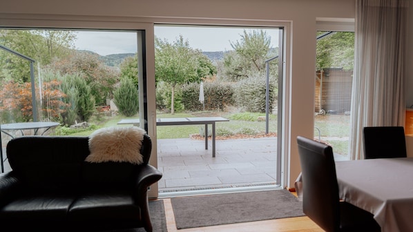 A room with a sliding glass door leading to an outdoor patio with a table and chairs.
