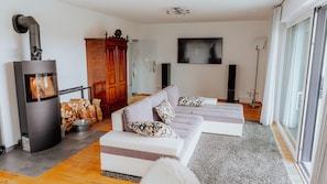 A modern living room with a sofa set, a fireplace, a large cabinet, and a sliding glass door.