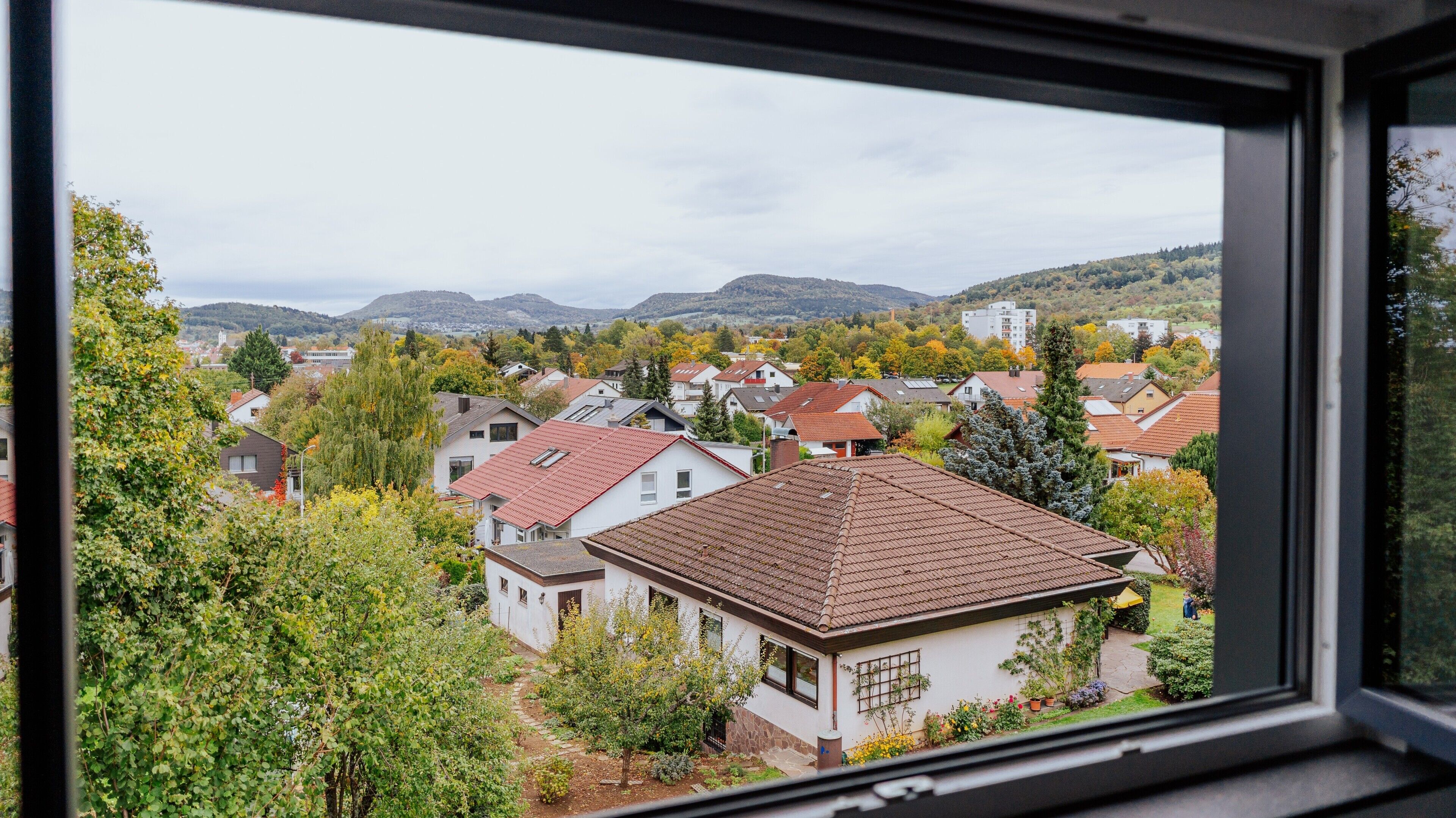 Zona residencial con casas, árboles y montañas a lo lejos.
