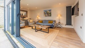 Ein modernes Wohnzimmer mit einer Couch, Sesseln, einem Couchtisch und einem Kamin.