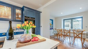 Eine moderne Küche mit blauen Schränken, einem eingebauten Backofen und einem Essbereich mit Holztischen und einer Tischplatte.